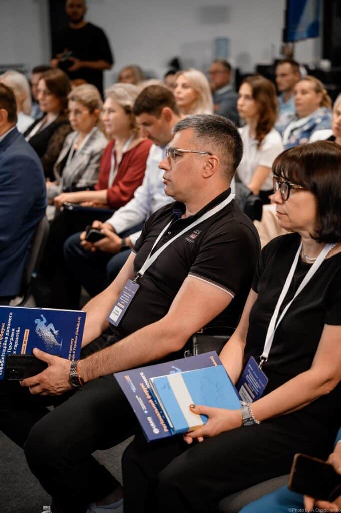 Люди на конференції з документами в руках.