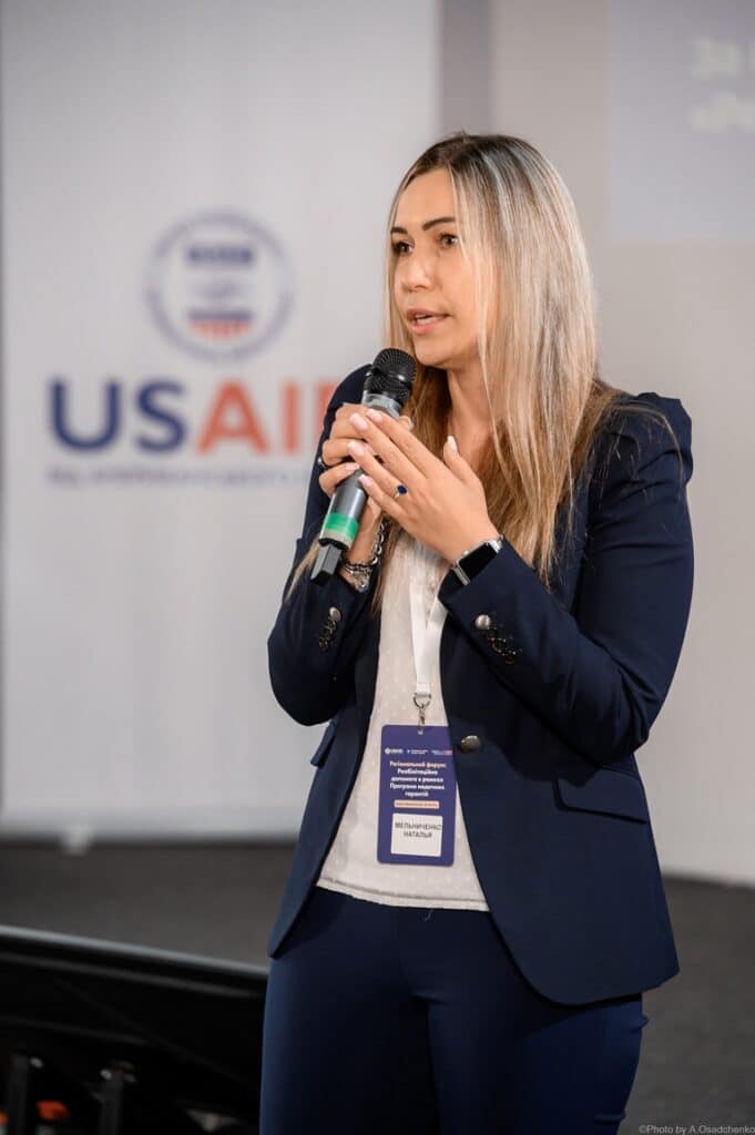 Жінка виступає з мікрофоном на форумі USAID