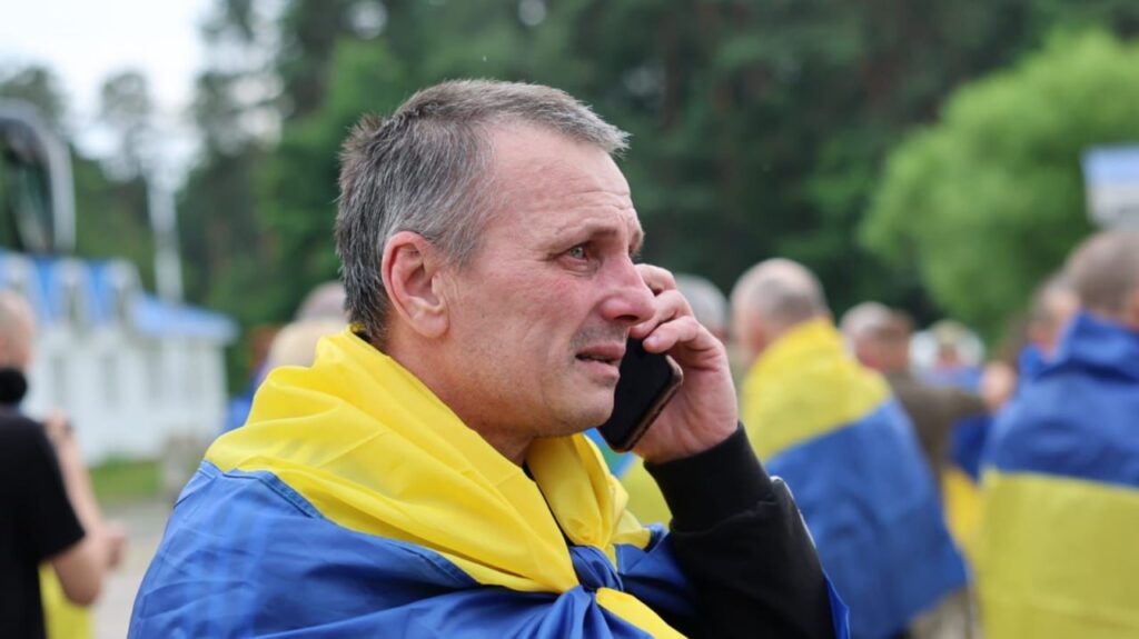 Чоловік з українським прапором розмовляє телефоном