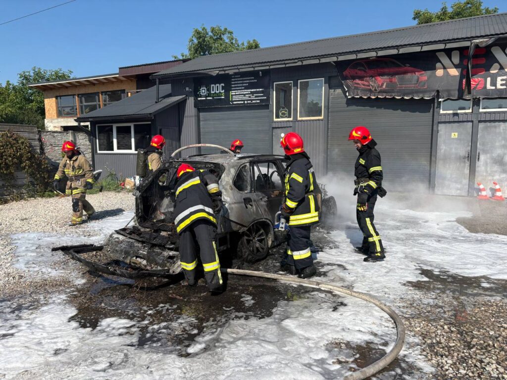 Пожежники гасять обгорілу машину біля автосервісу.