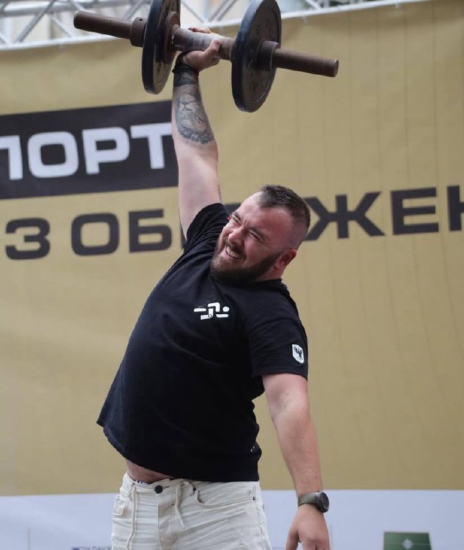 Чоловік піднімає штангу на змаганнях.