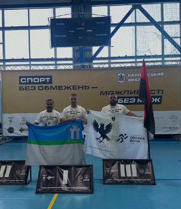 Три чоловіки з прапорами на спортивному заході.