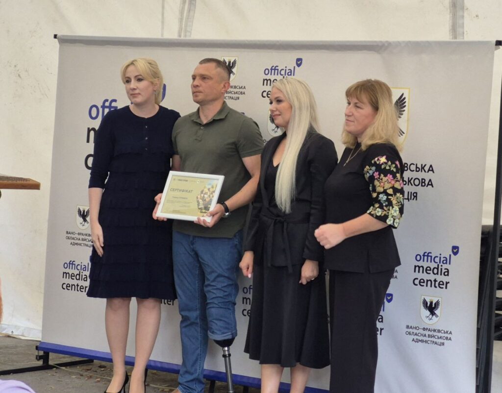 Чотири людини, чоловік з сертифікатом на сцені.