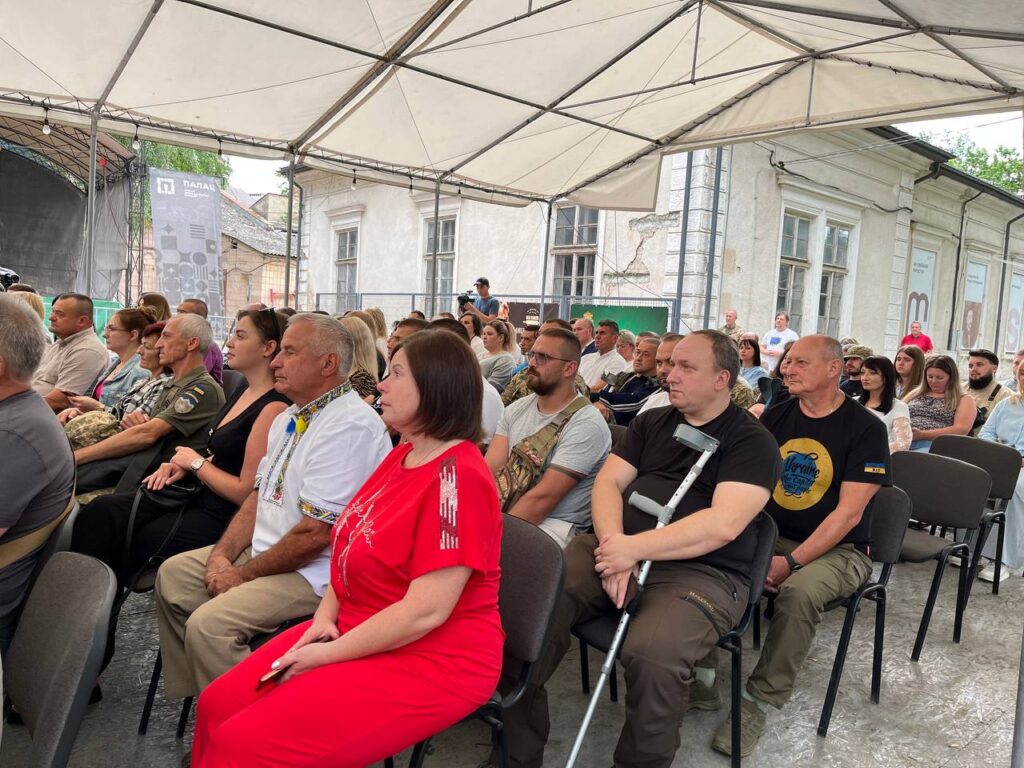 Люди сидять на заході під тентом.