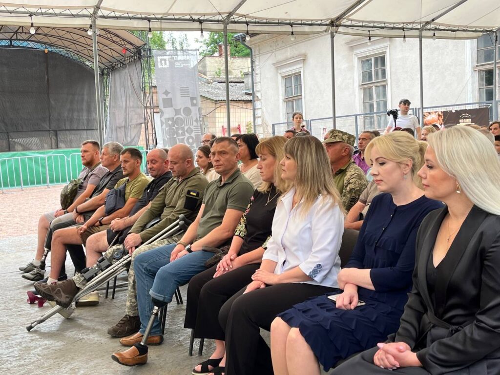 Люди сидять на вуличному заході в наметі.