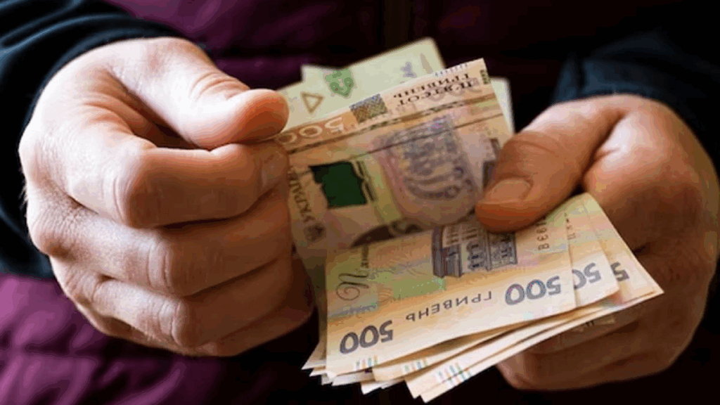 Людина рахує українські гривні в руках.