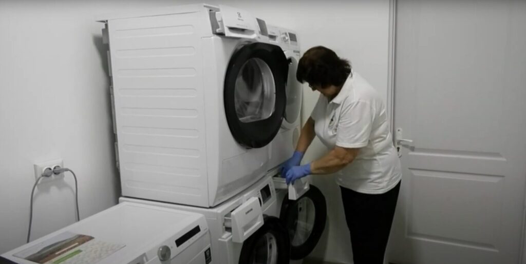 Жінка використовує пральну машину у пральні