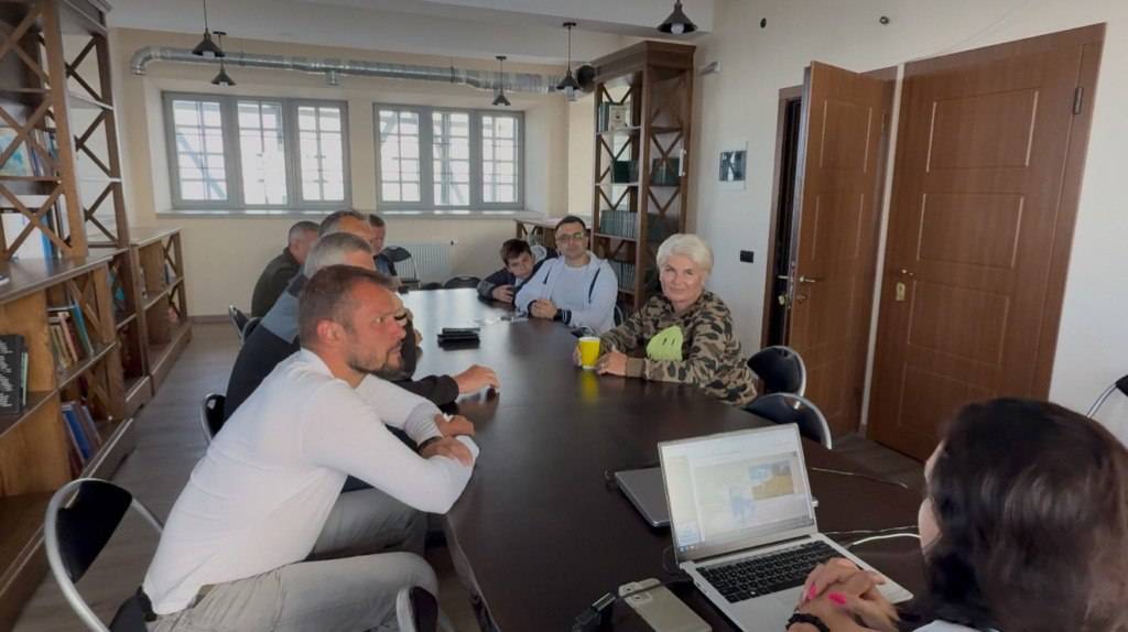 Люди на зустрічі в офісі, навколо столу.