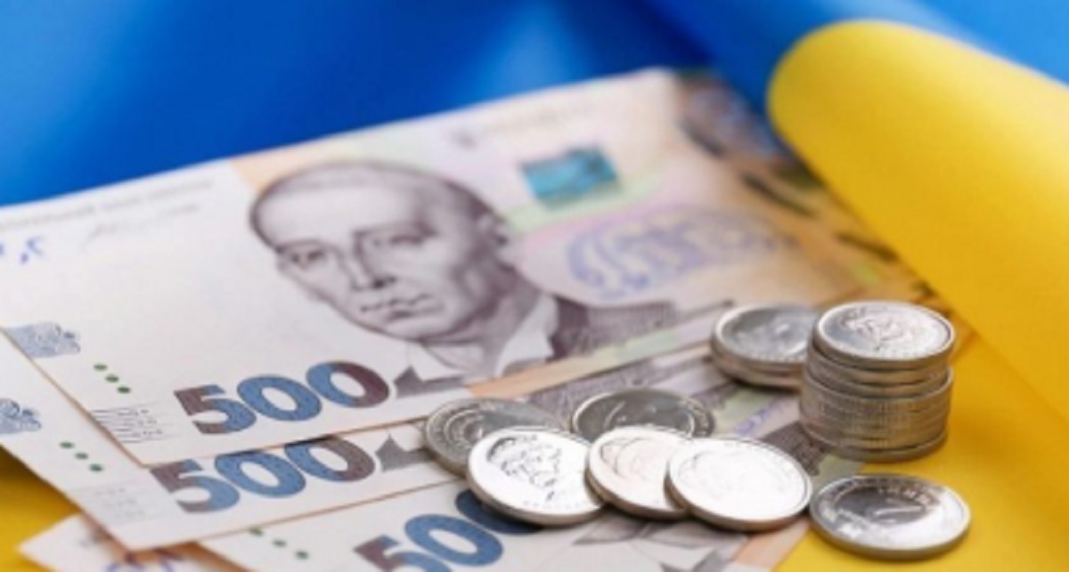 Українські банкноти та монети на фоні прапора