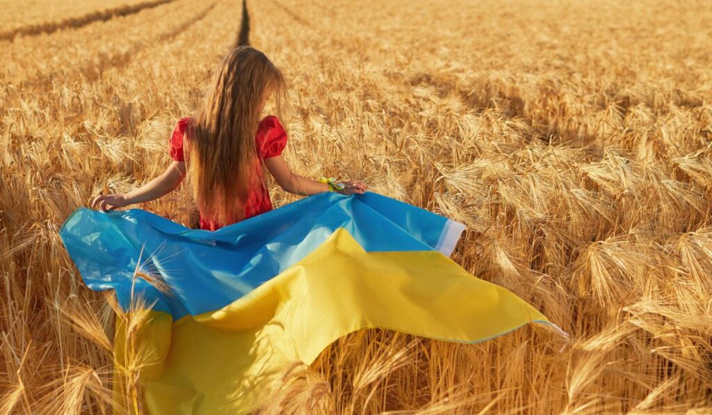 Дівчина з прапором України у пшеничному полі.
