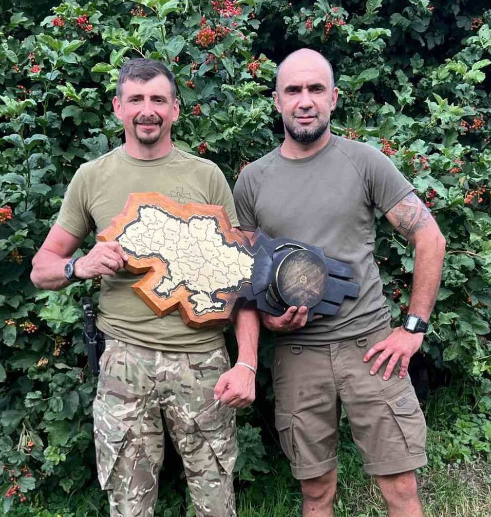 Двоє чоловіків із картою України на природі.