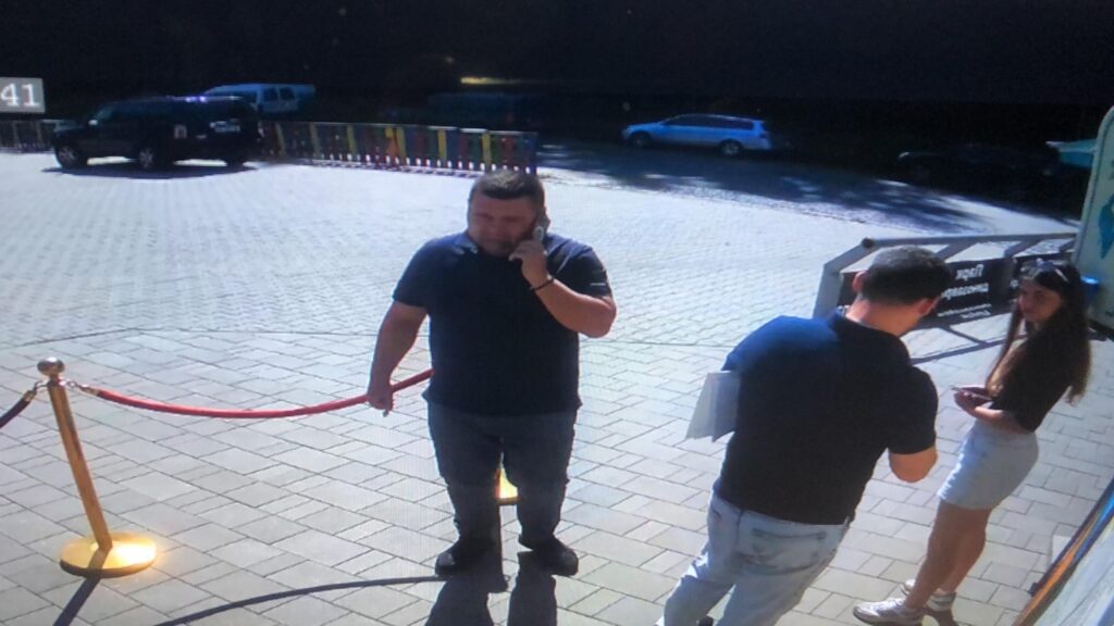 Людина з телефоном на площі біля авто