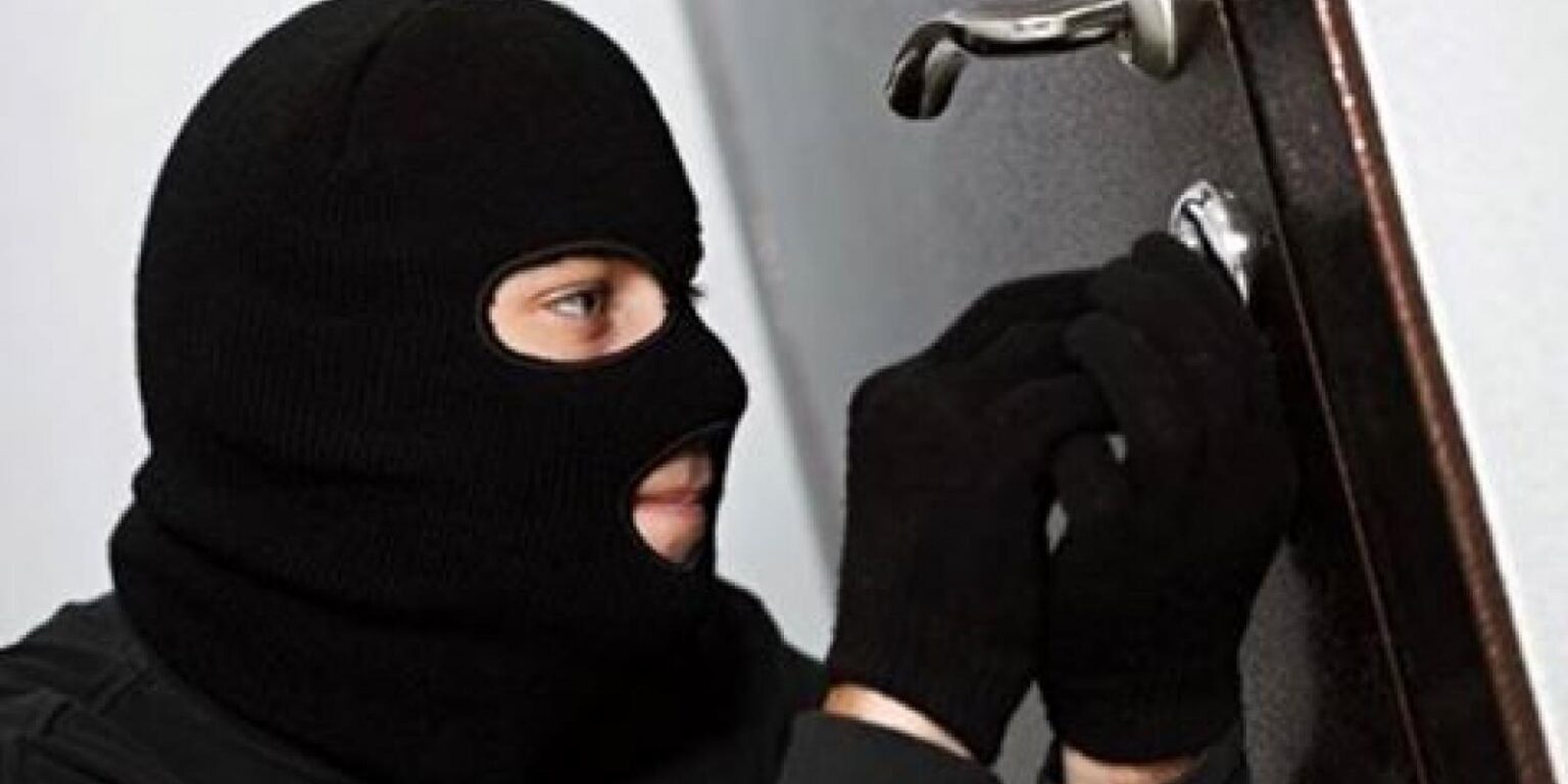 Людина в масці намагається відімкнути двері.