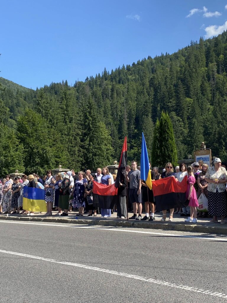 Люди з прапорами на дорозі в горах.