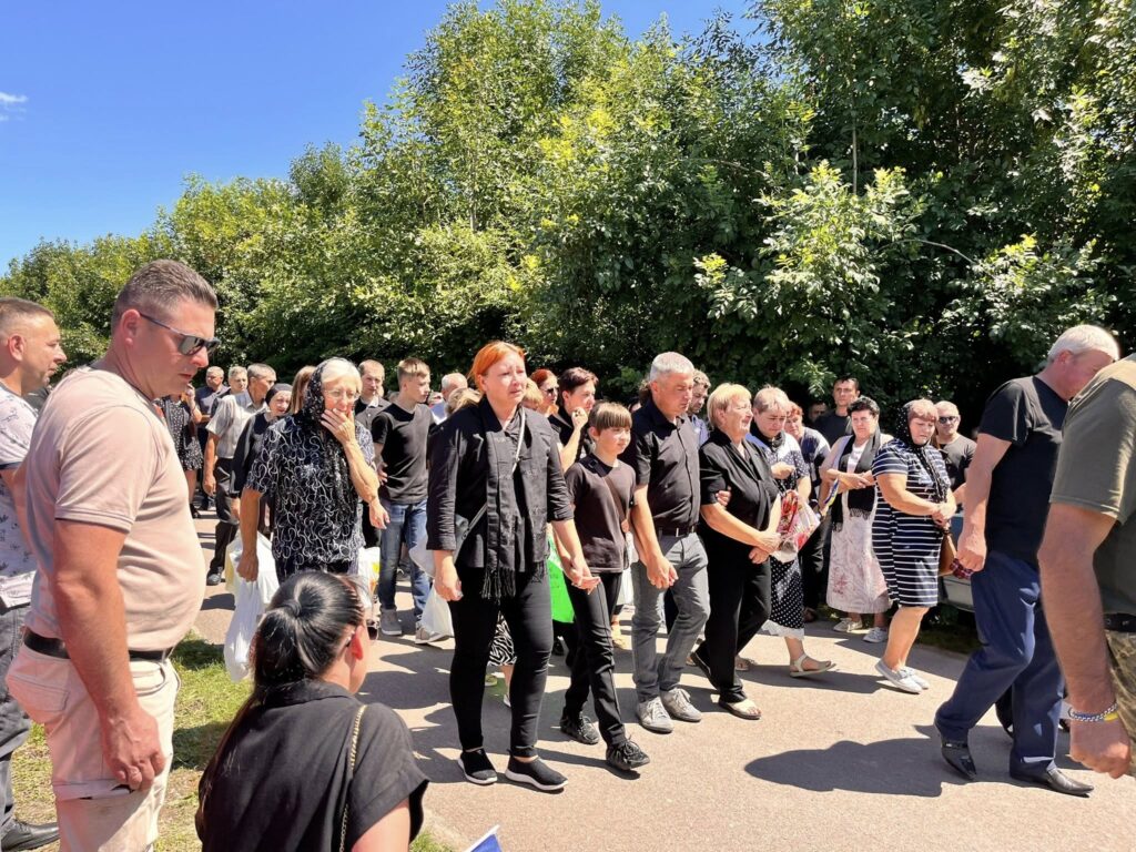 Група людей йде на вулиці під сонцем.