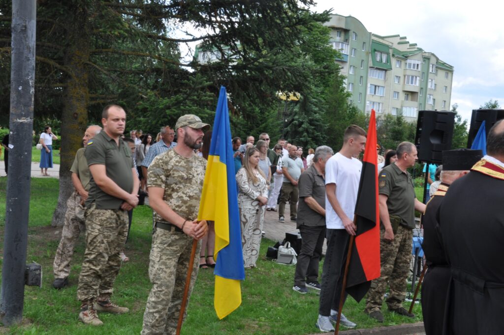 Люди на мітингу з українськими прапорами на вулиці.