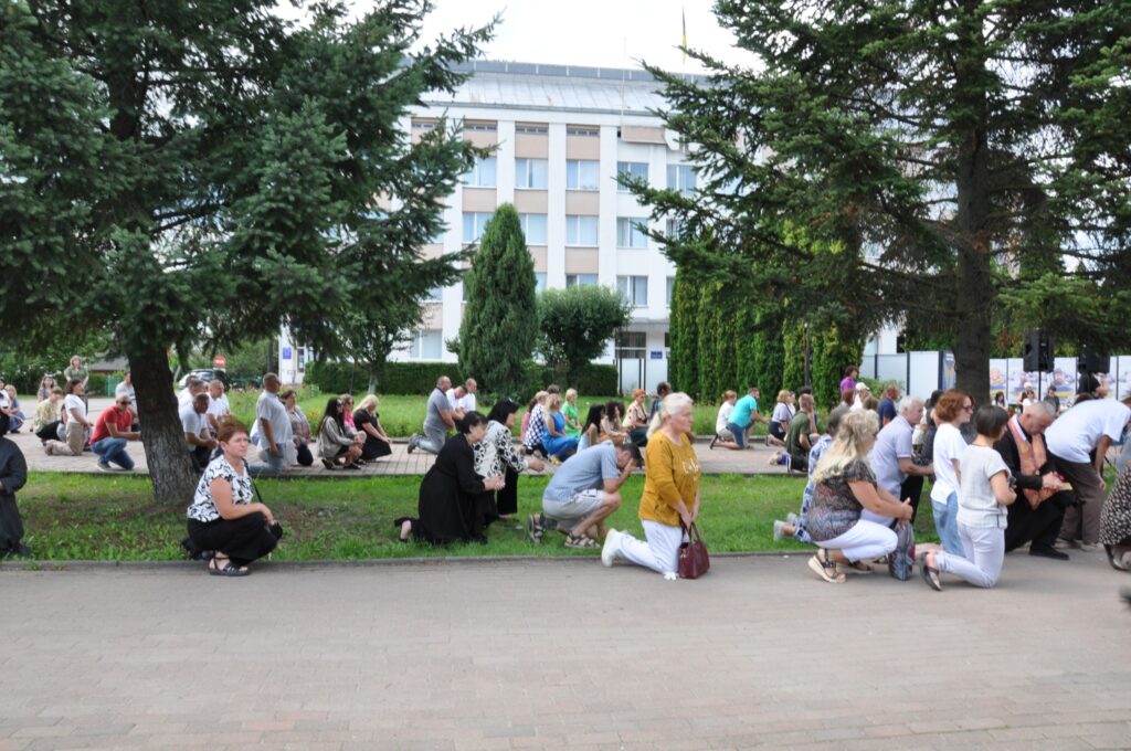 Люди на колінах перед будівлею