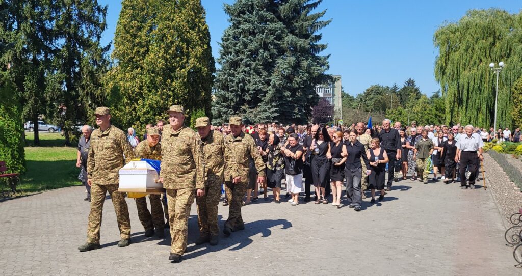 Процесія з труною в парку на похованні.