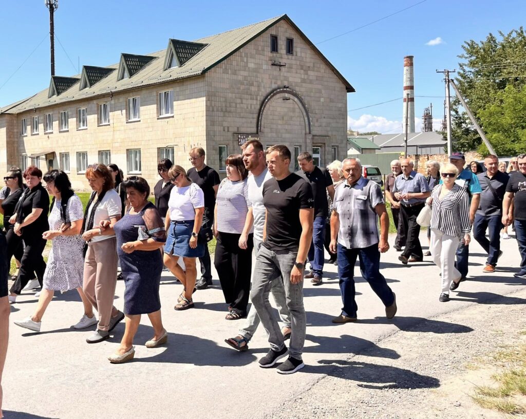 Люди йдуть вулицею перед старою будівлею.