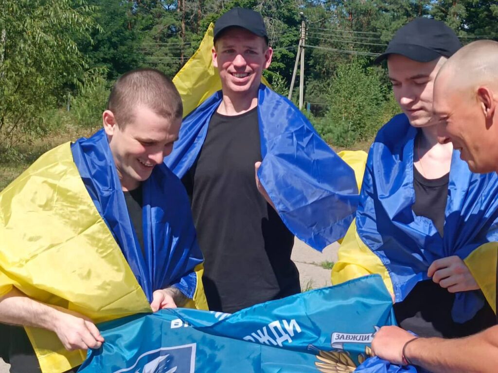 Люди з українським прапором на вулиці веселяться