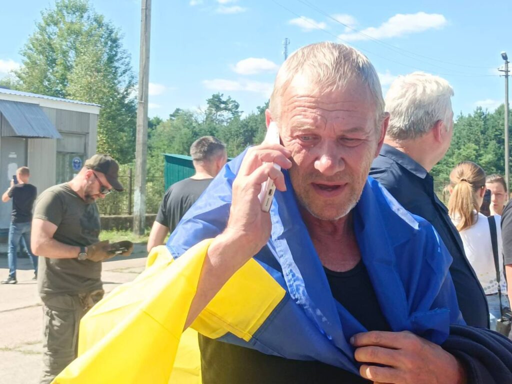 Людина з прапором України говорить по телефону.
