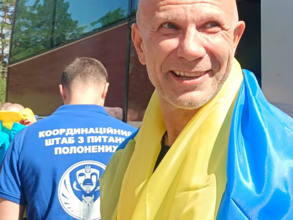 Чоловік в синьо-жовтому прапорі з усмішкою