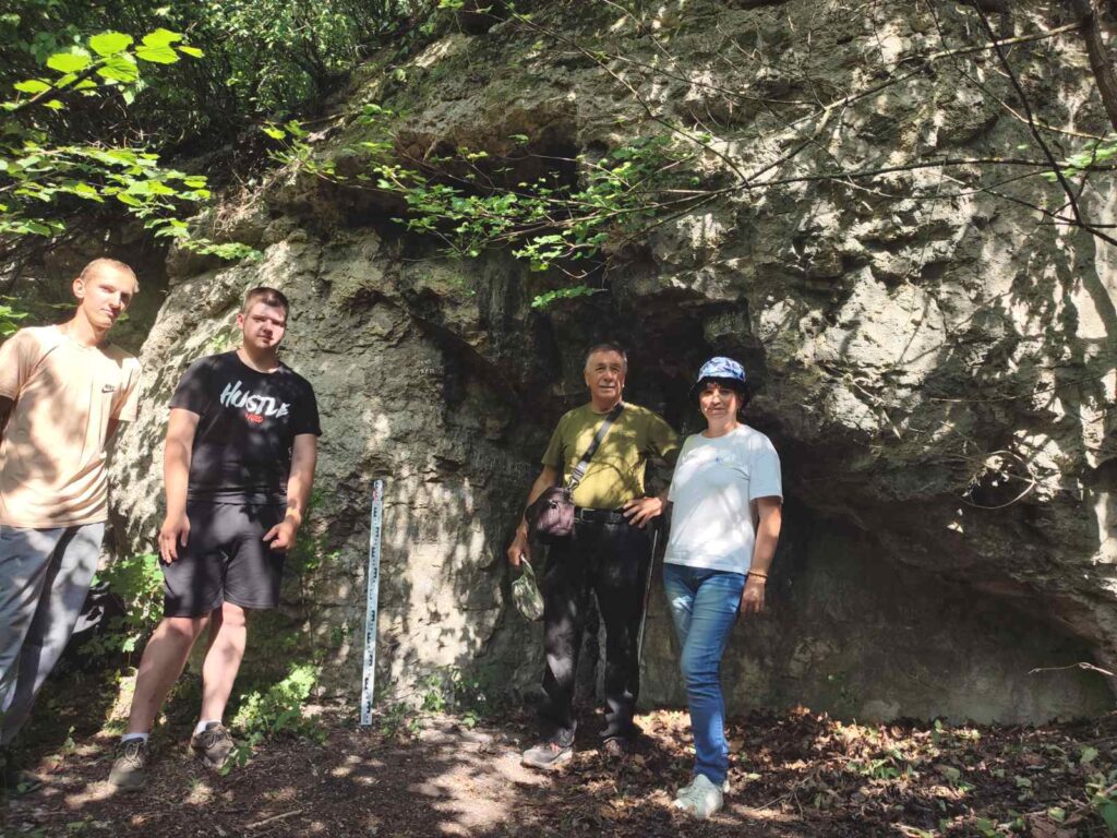 Люди перед скелястою стіною в лісі