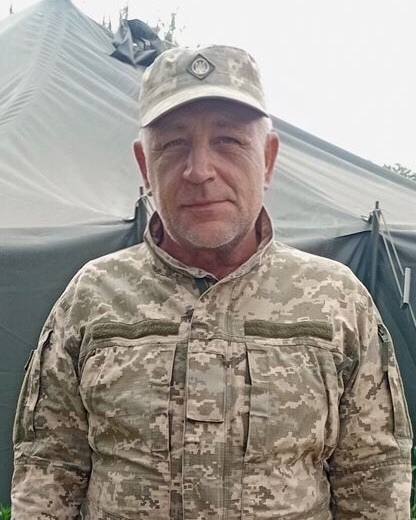 Чоловік у камуфляжі біля намету.