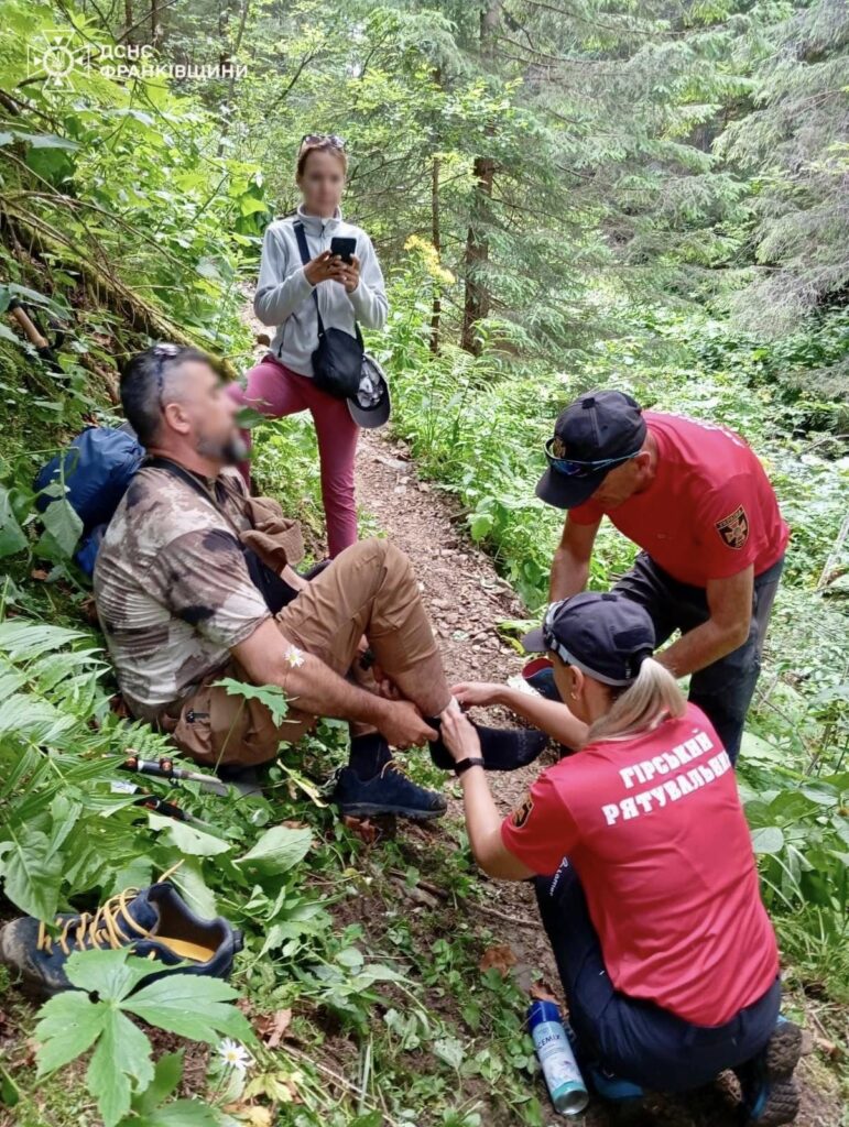 Гірські рятувальники допомагають туристу в лісі.