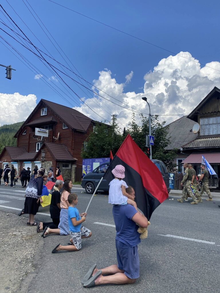 Люди на колінах із прапорами на вулиці