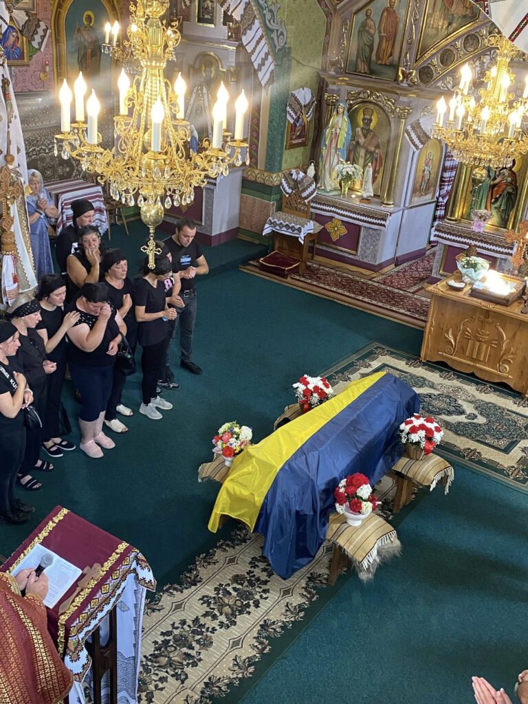 Церемонія прощання з труною, покритою прапором України.