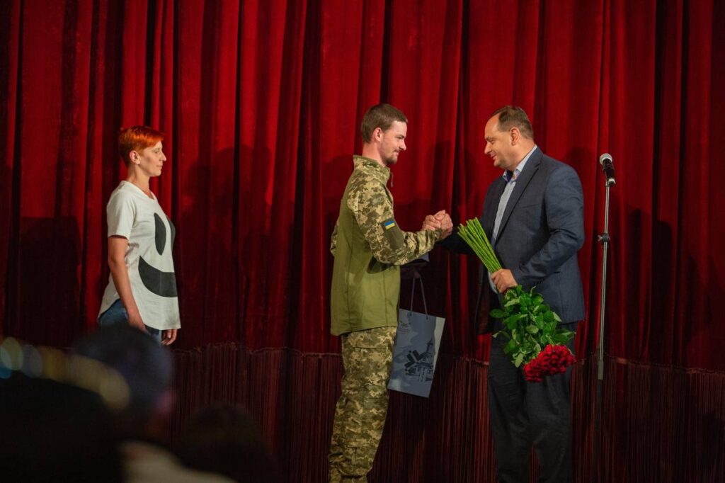 Церемонія вручення квітів військовому на сцені.