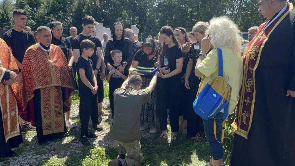 Люди під час церемонії на вулиці, священики поруч.