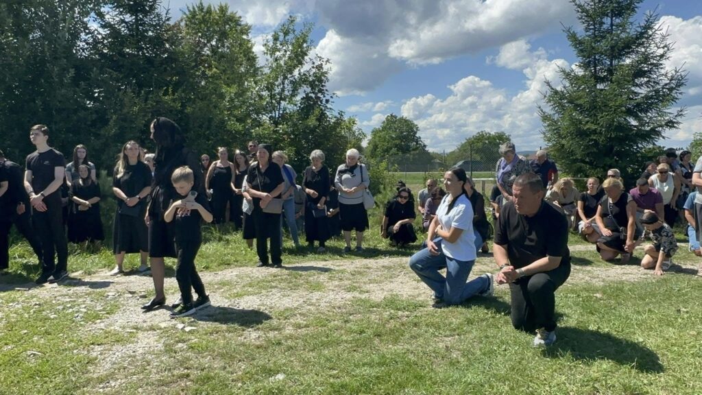 Люди стоять і сидять на колінах на природі.