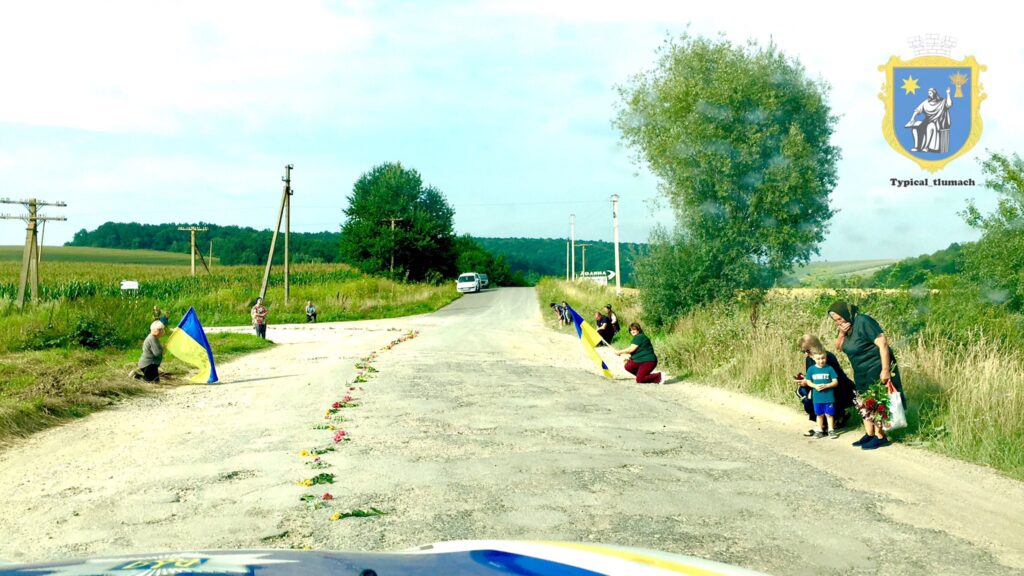 Люди з українським прапором на сільській дорозі