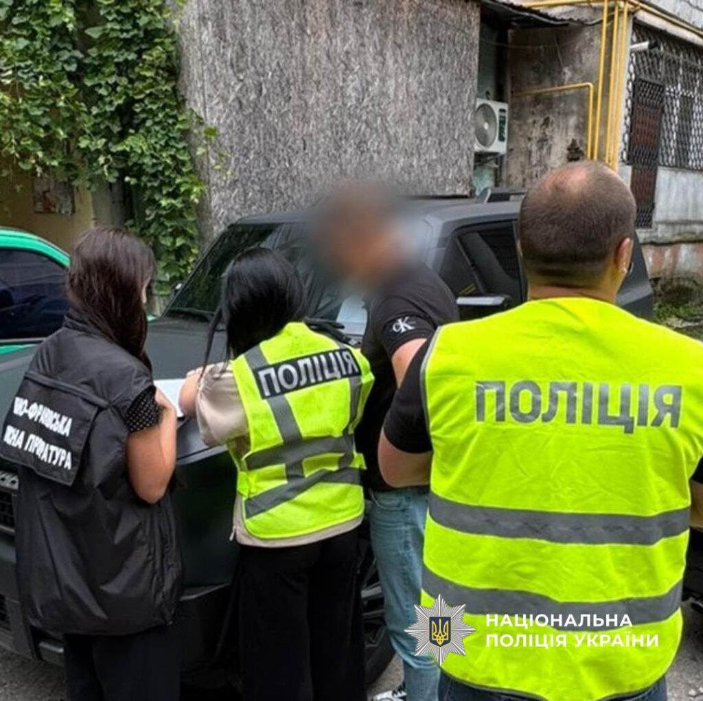 Поліція затримує особу на вулиці біля авто.