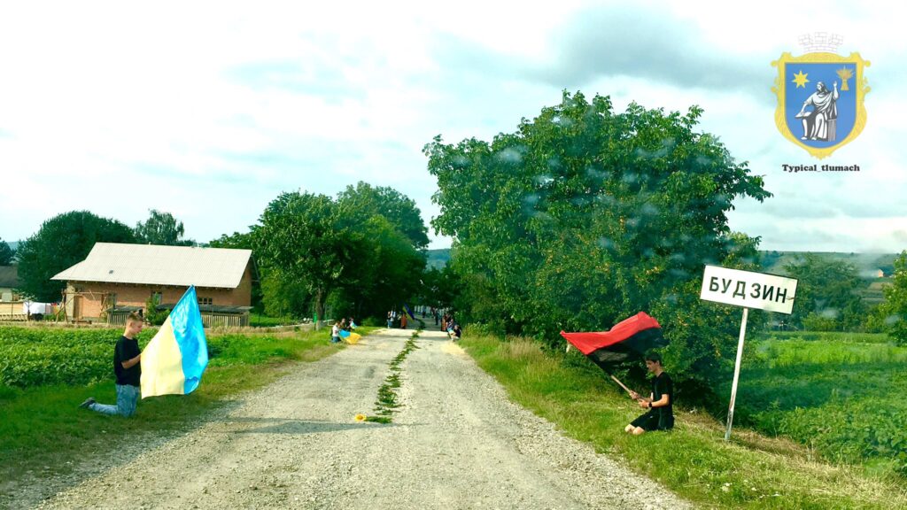 Люди з прапорами на дорозі в селі.
