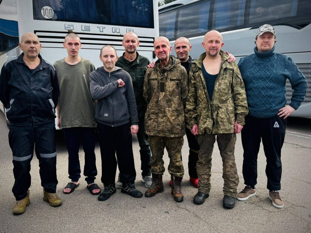 Група людей перед автобусами, різний військовий одяг.