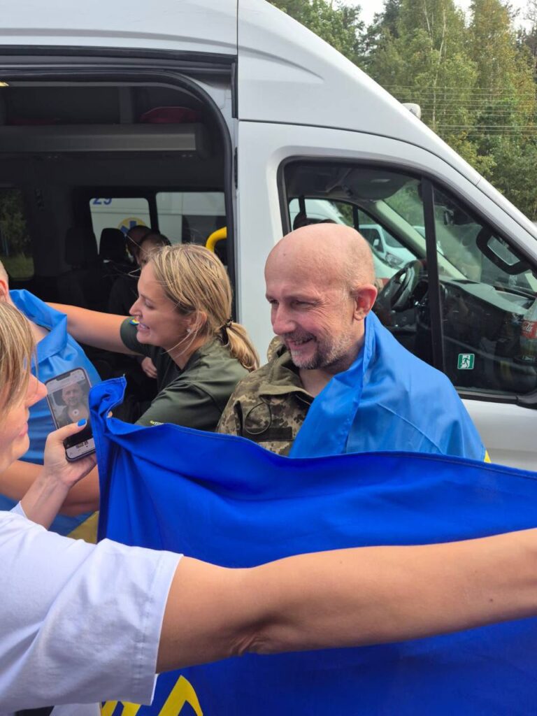 Люди з українським прапором біля мікроавтобуса