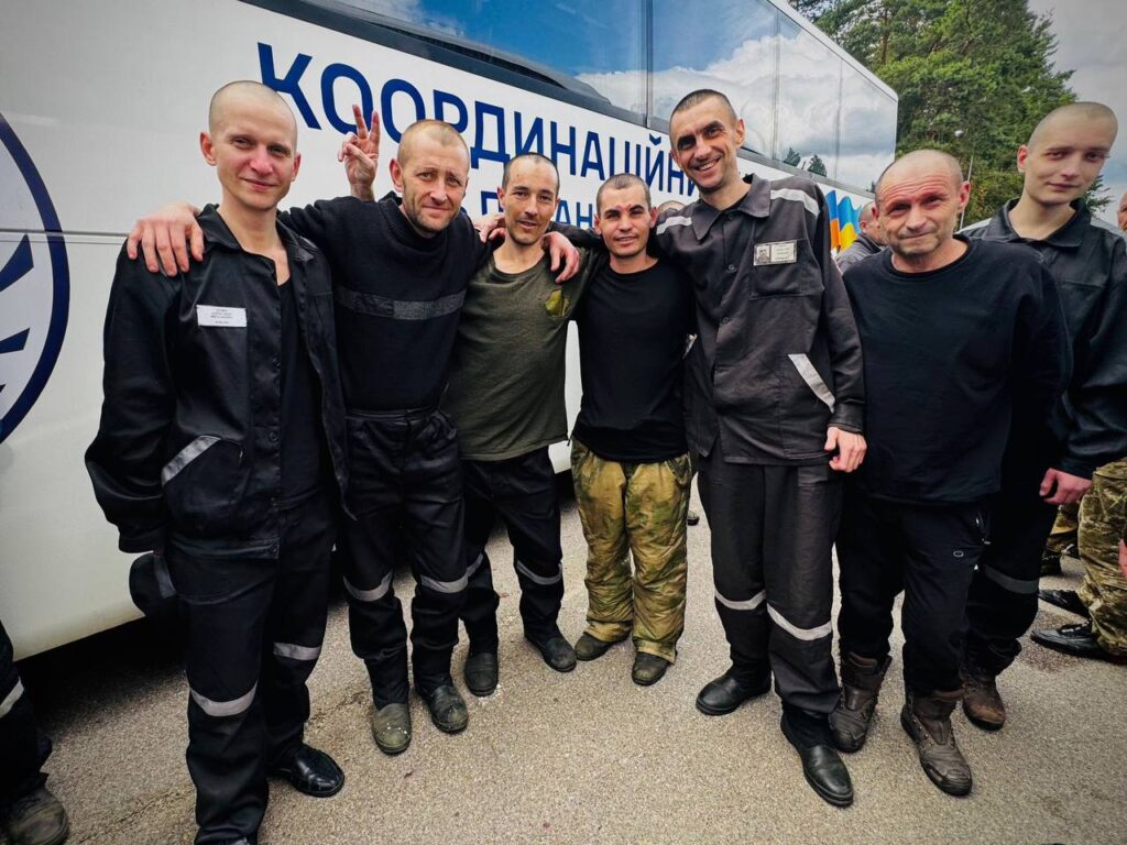 Група людей перед автобусом на відкритому повітрі.