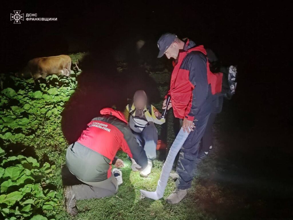 Рятувальники допомагають людині вночі на полі.