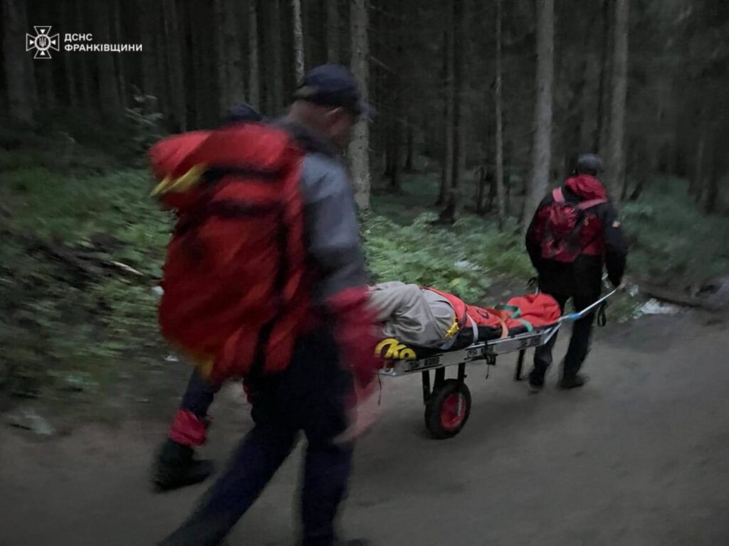 Рятувальники транспортують людину на ношах в лісі.