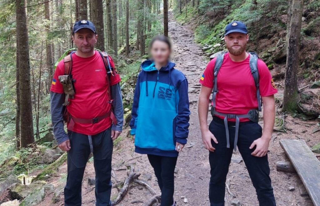 Троє людей у горах на лісовій стежці.