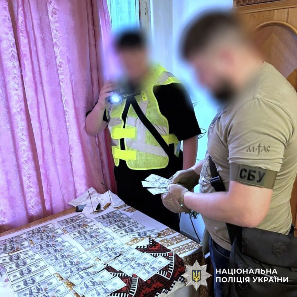 СБУ оглядає долари на столі у кімнаті.
