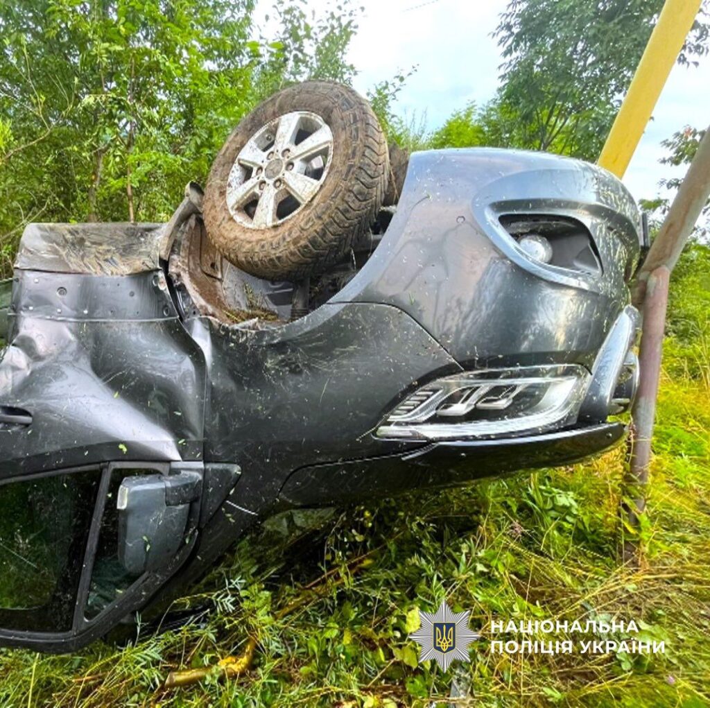 Перевернутий автомобіль на траві біля дороги.