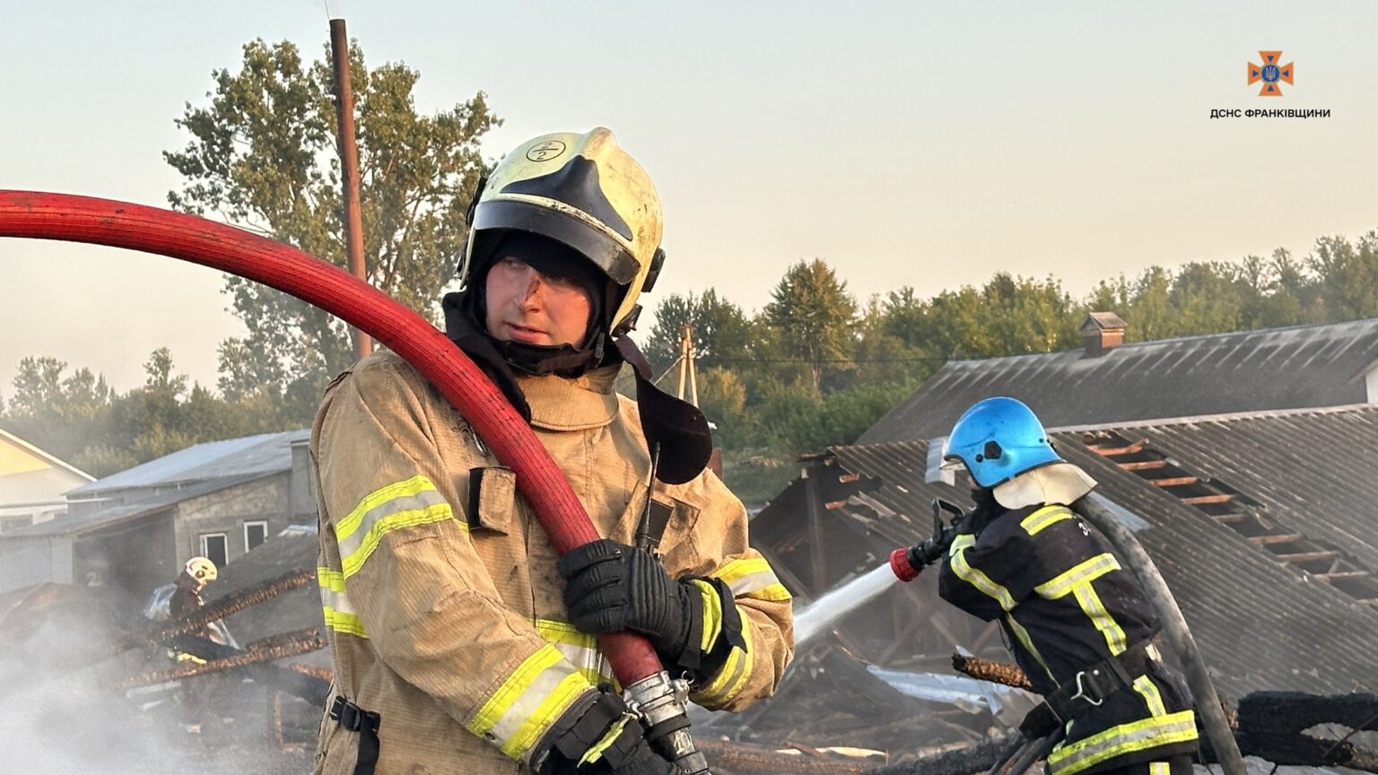 Пожежники гасять пожежу будівлі на тлі дерев