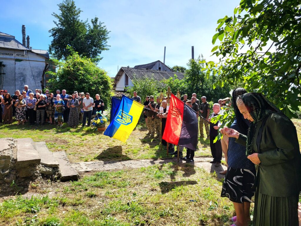 Українська громада з прапорами на зібранні.