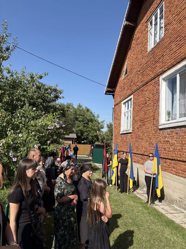 Люди на подвір'ї з українськими прапорами