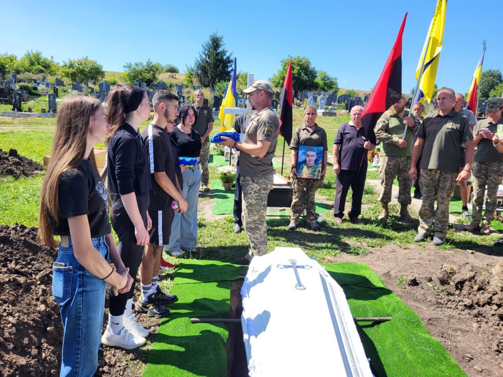 Похоронна церемонія з військовими та прапорами в Україні.