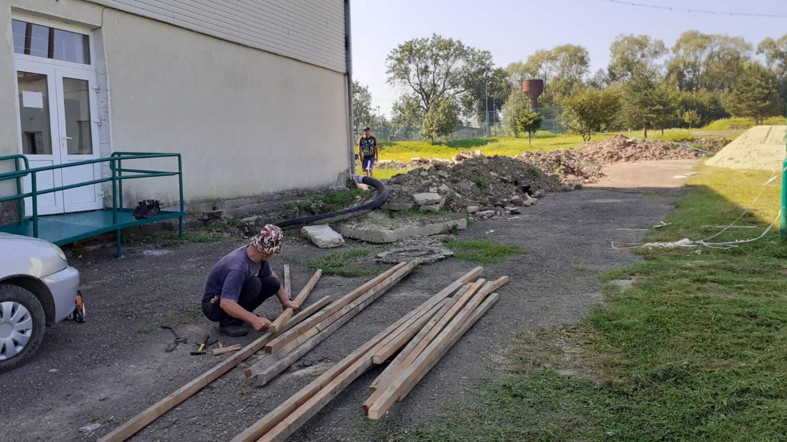 Будівництво біля будівлі, чоловік працює з деревом.